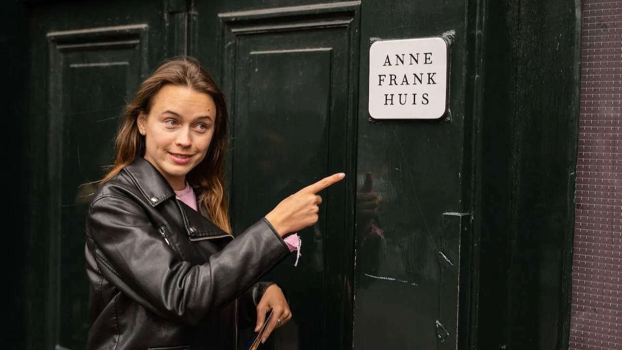 Woman standing outside the Anne Frank House along the Amsterdam canal streets