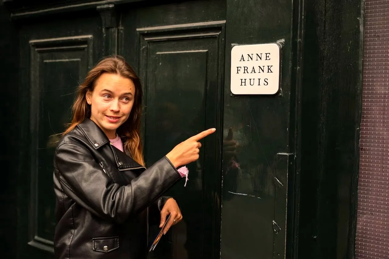 A guest pointing at the Anne Frank Huis name sign on a dark green door