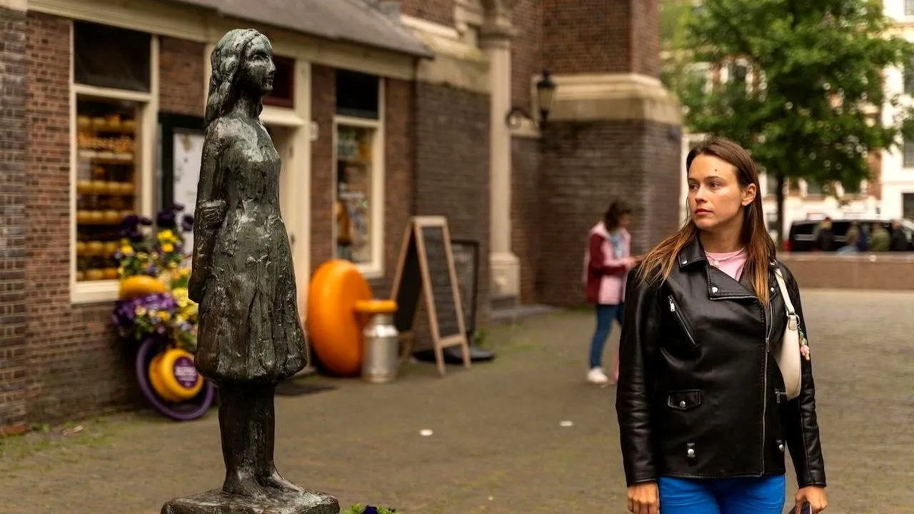 A woman standing by the Anne Frank statue at Westermarkt in Amsterdam