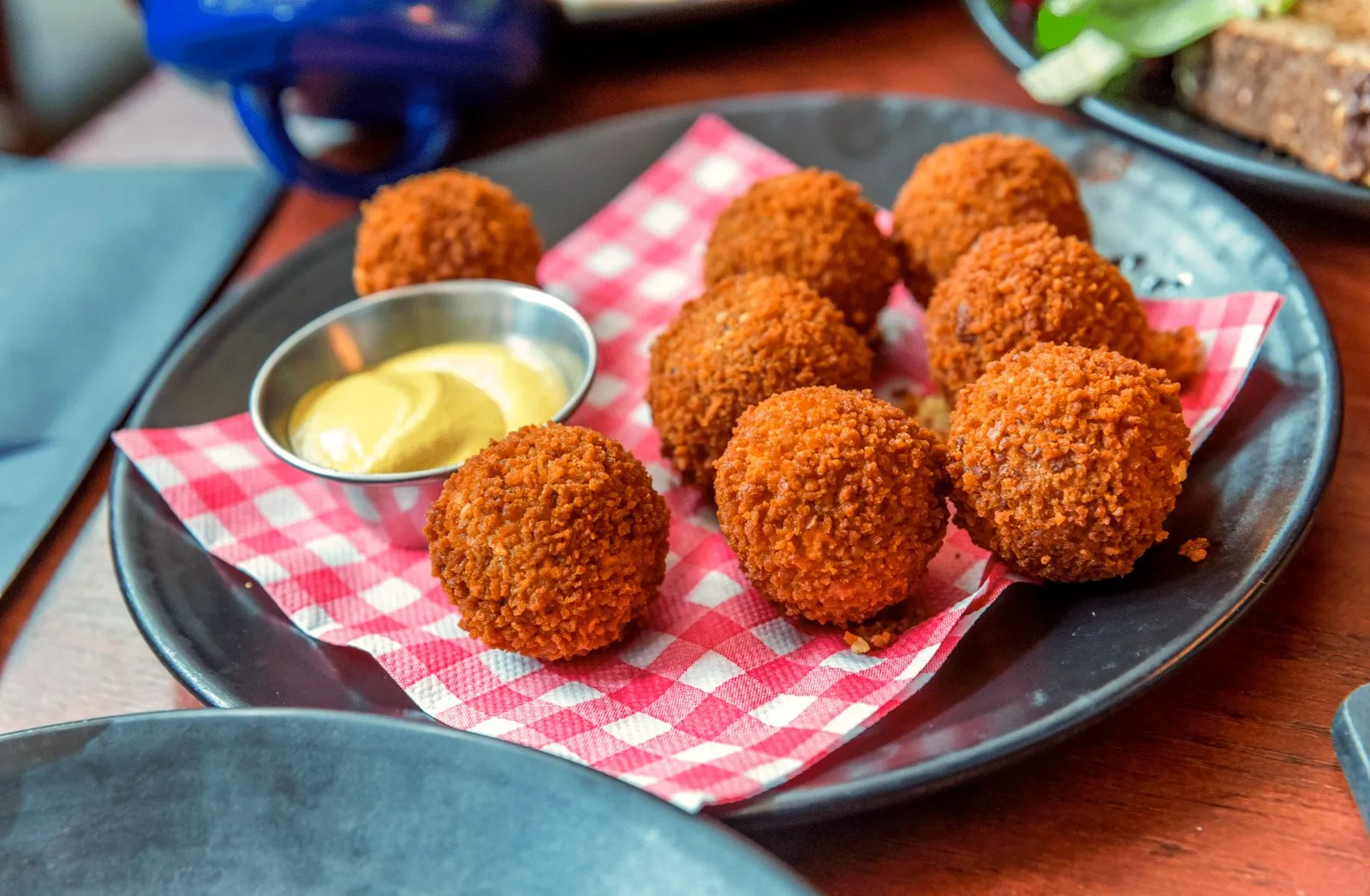 Plate of crispy Dutch bitterballen with mustard on red checkered paper