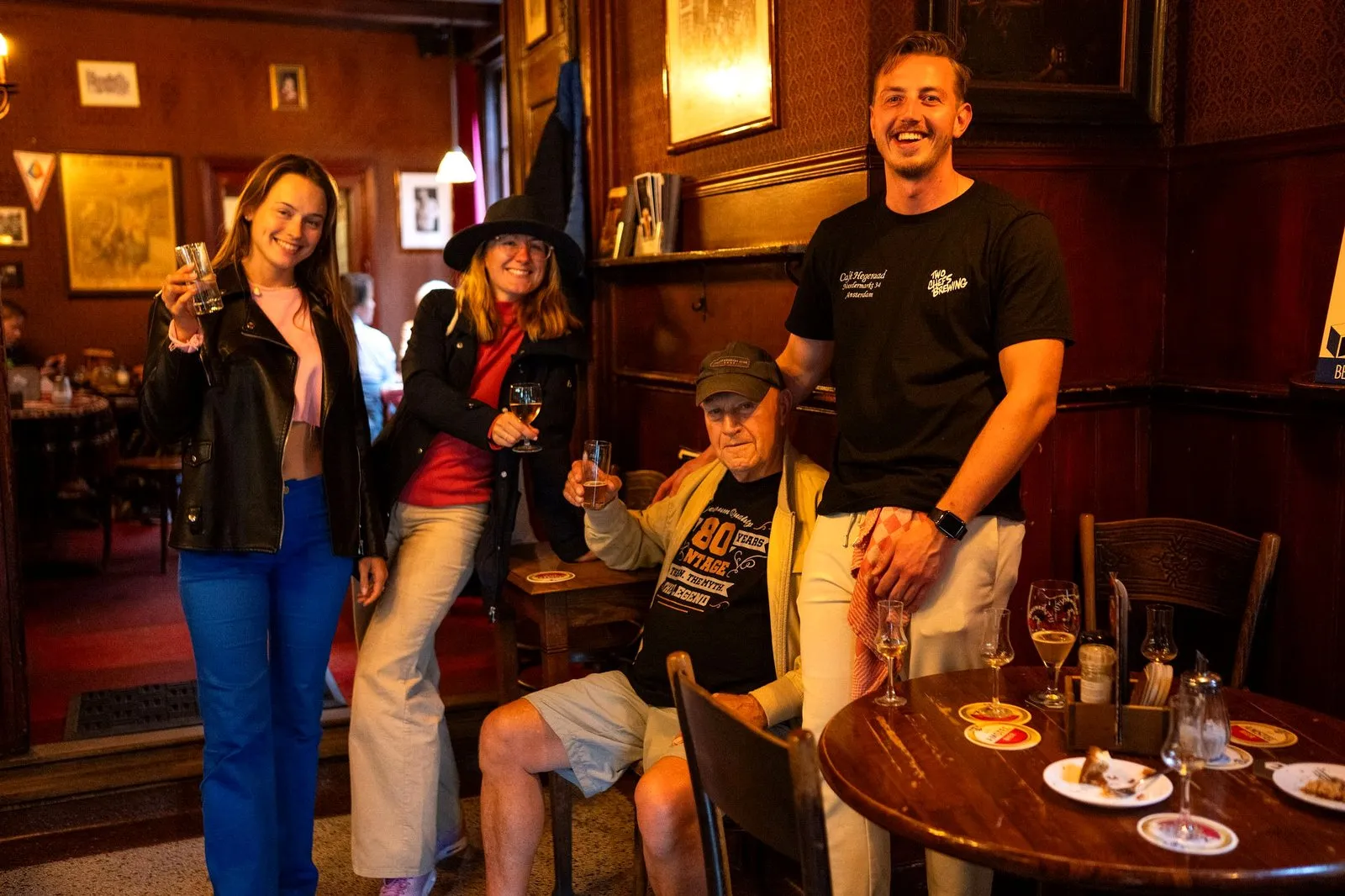 A guide and guests raising beers in the cosy Hegeraad brown bar in Amsterdam