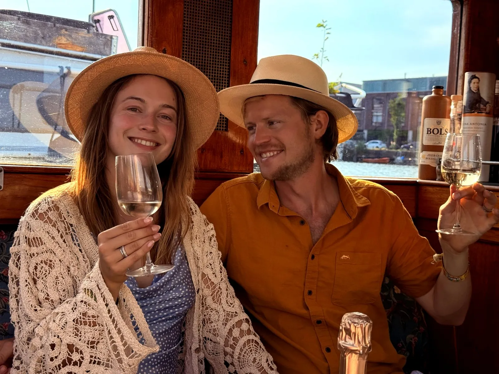A couple raising their glasses together in the warm cabin of an Amsterdam canal boat