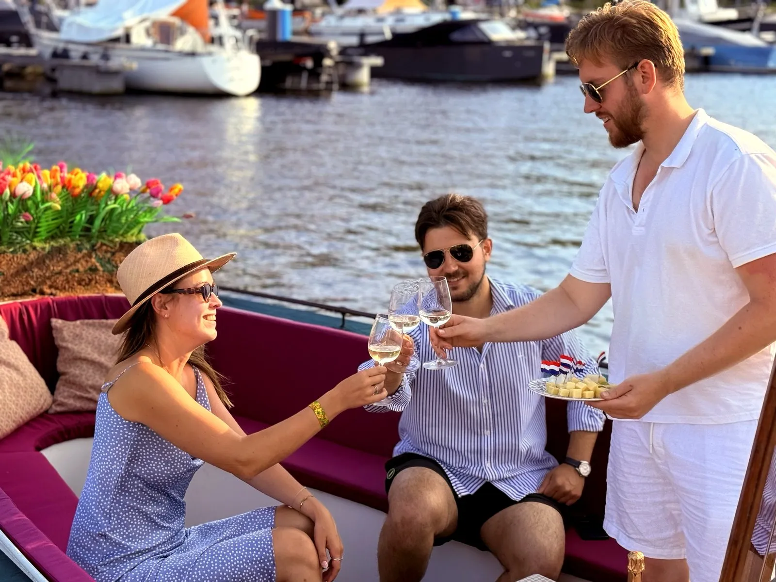 Three guests toasting white wine on an Amsterdam canal boat by the tulips
