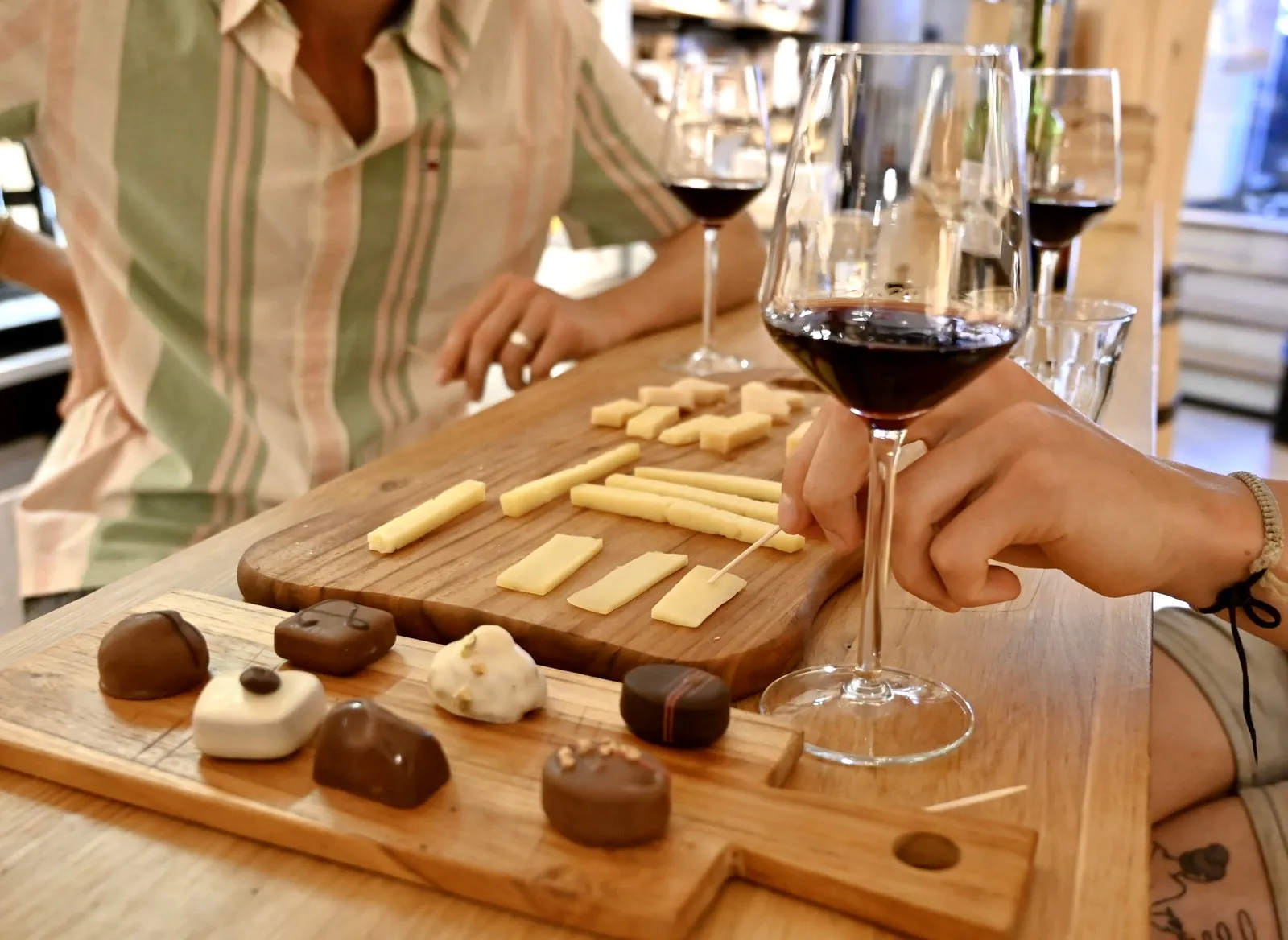 A board of Dutch cheese and chocolates with two glasses of red wine on a table