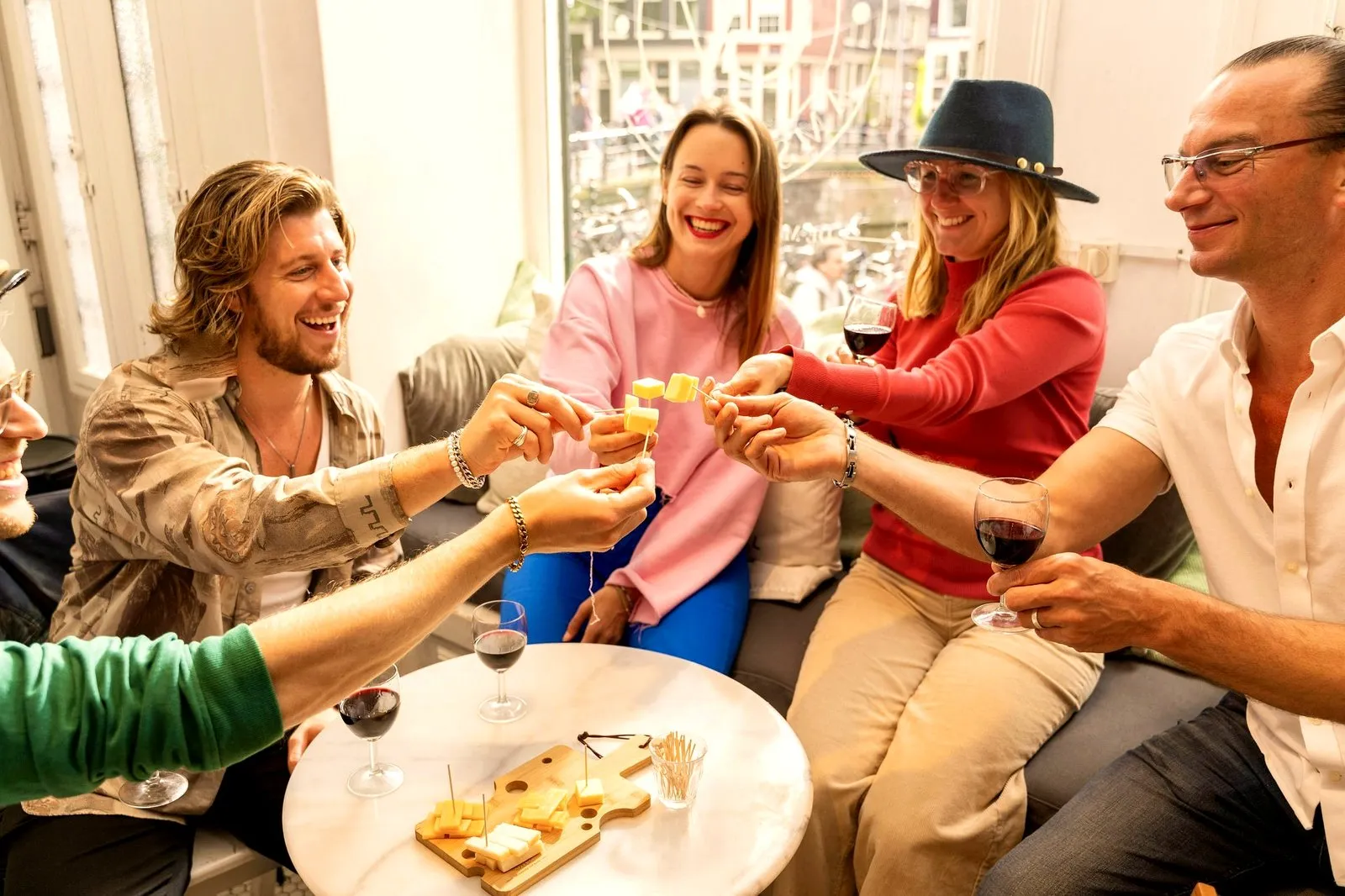 A team toasting jenever and wine over a cheese board in a bright Amsterdam tasting room