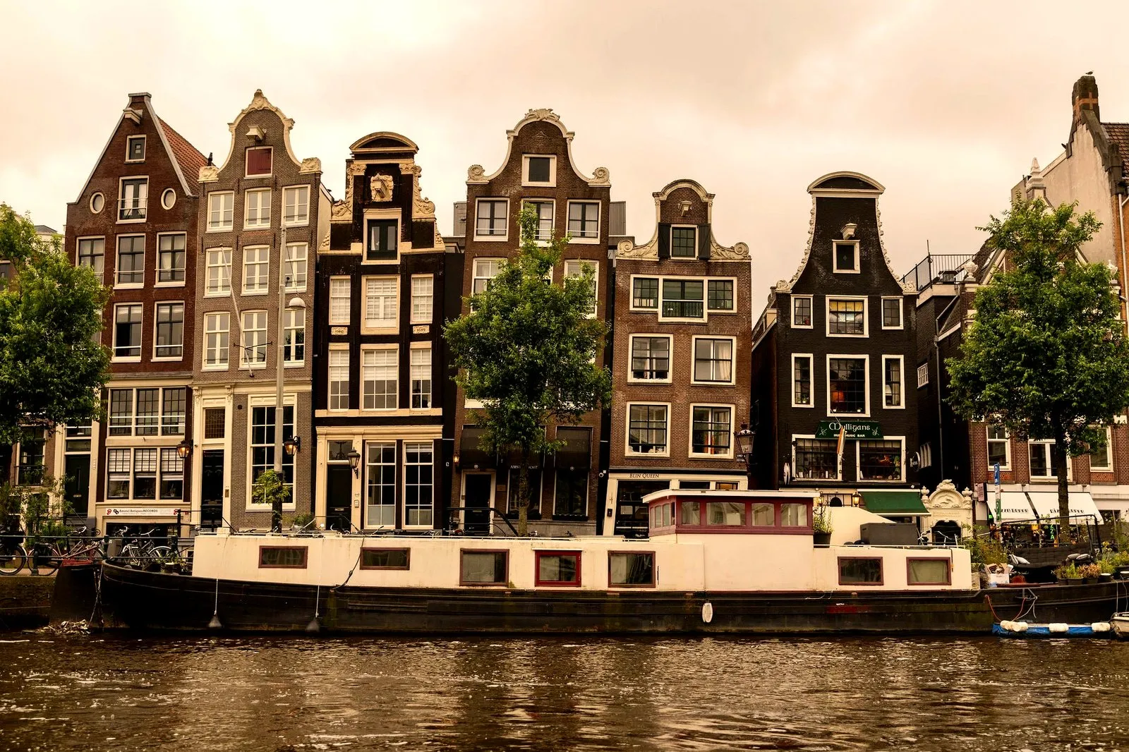 Crooked Amsterdam canal houses with a houseboat in front