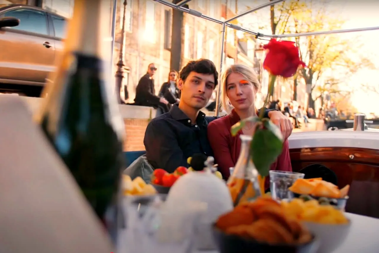 A couple at a dinner table with a red rose on a private Amsterdam canal boat