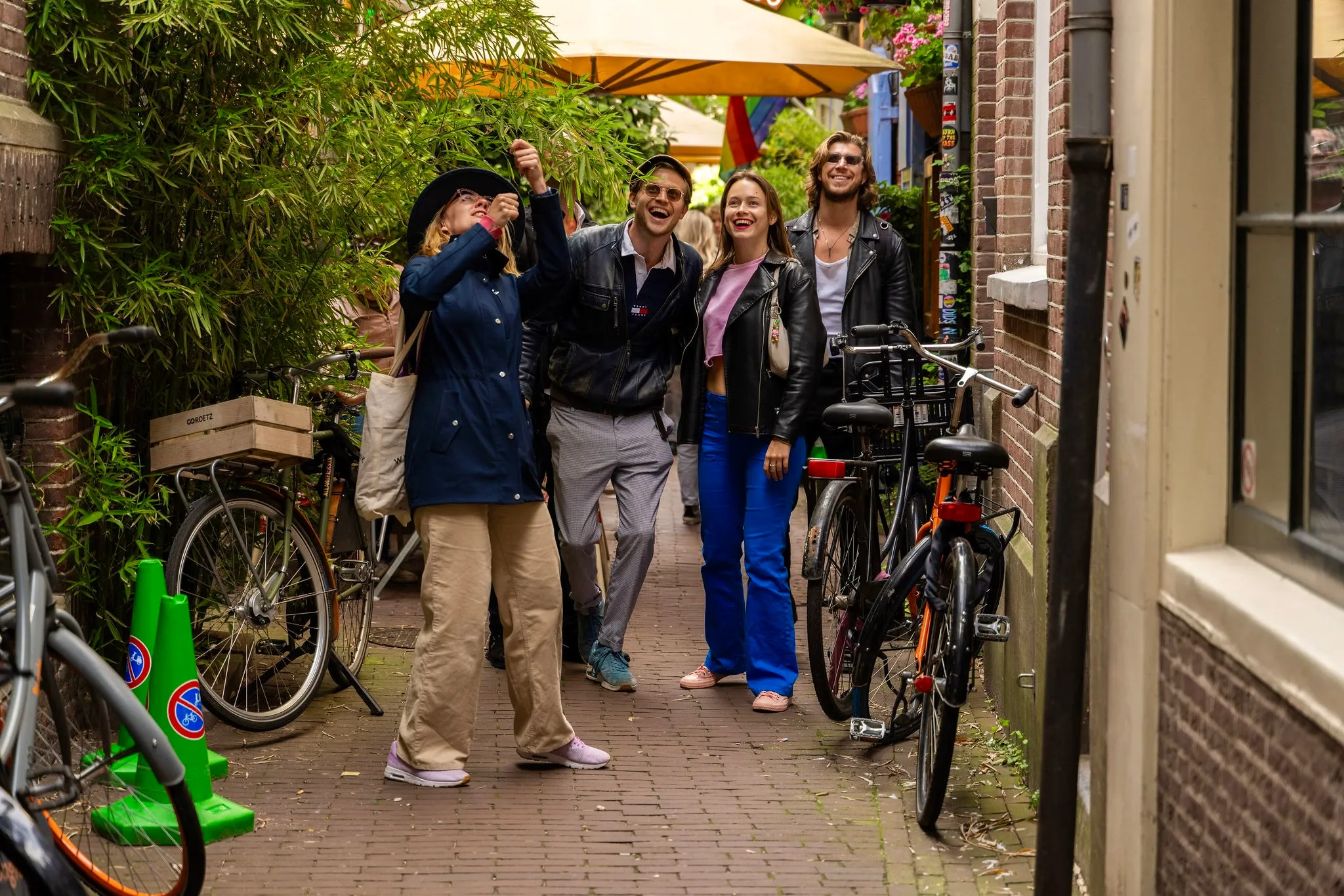Four guests laughing as they walk down a narrow Amsterdam alley lined with parked bikes