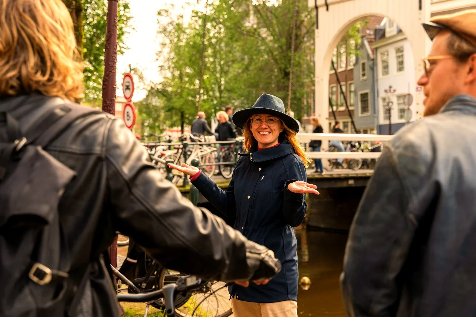 An Adam and Eve guide telling a story to guests on an Amsterdam canal bridge