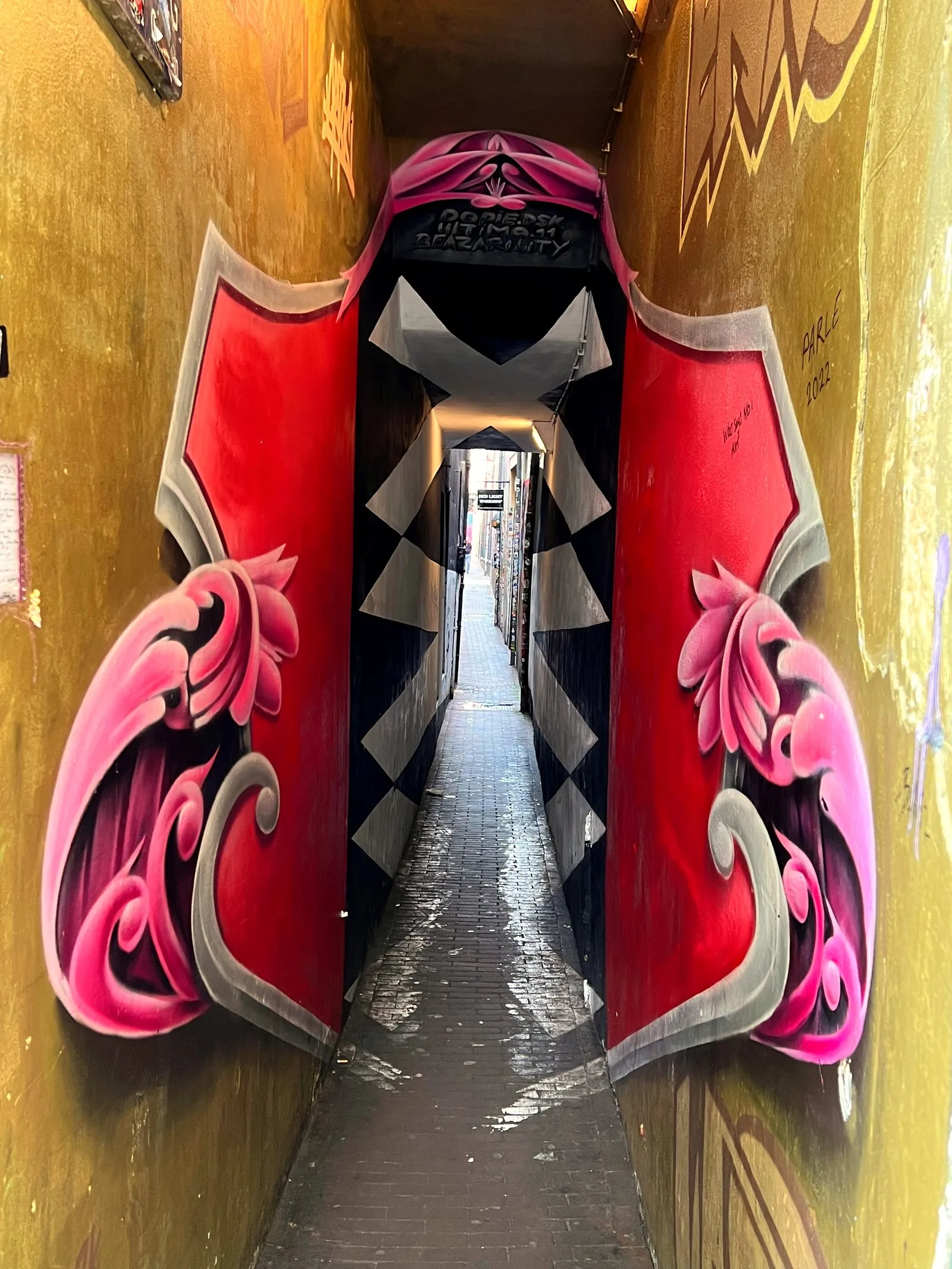 Amsterdam's narrowest alley framed by a red and pink mural