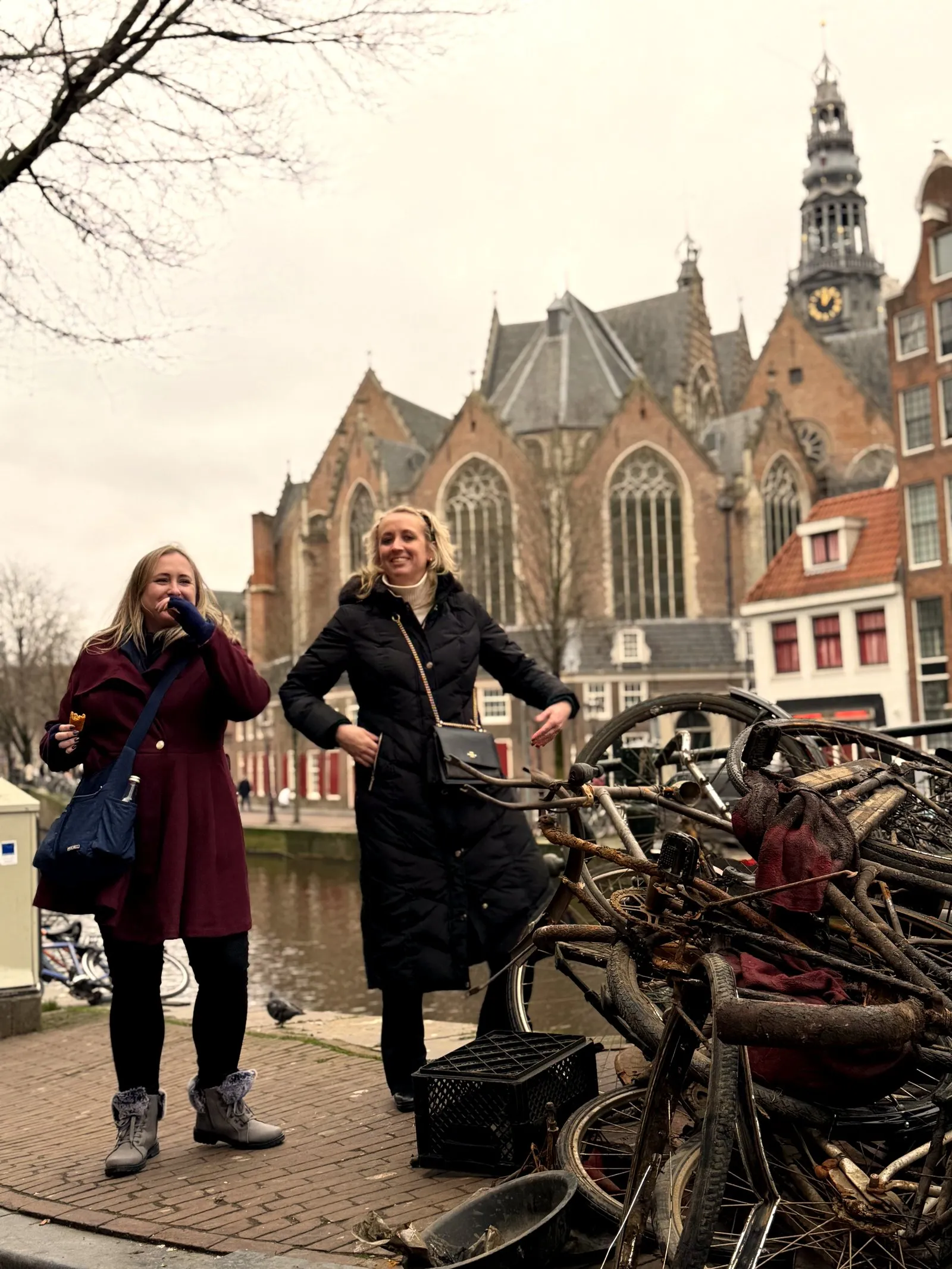 Two guests by a pile of old bikes with the Oude Kerk church behind on the food tour