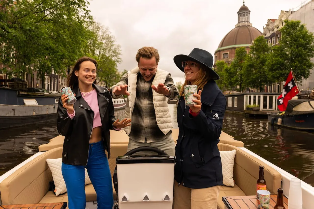Three guests laughing with drinks on a private Amsterdam canal boat