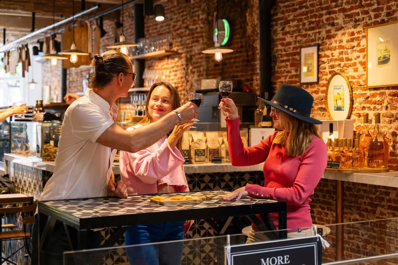 Three guests toasting glasses of wine at a brick-walled Amsterdam tasting bar