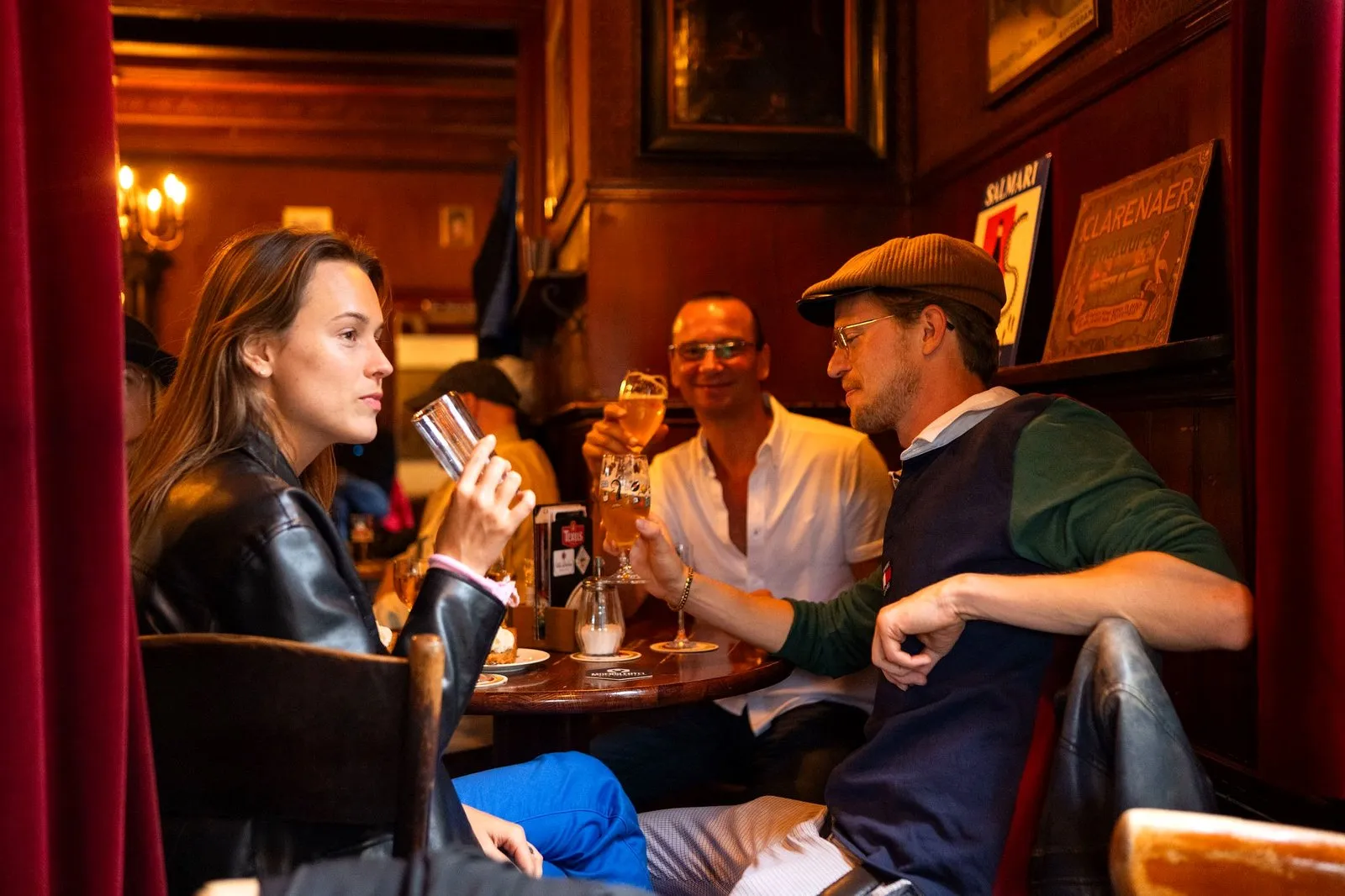 Guests tasting drinks in an old Amsterdam tasting room with red curtains and antique paintings