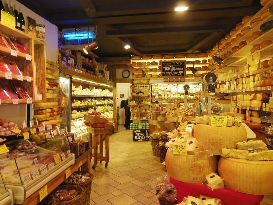 Cheese shop interior stacked floor to ceiling with Gouda wheels, parmesan, sausages and deli goods