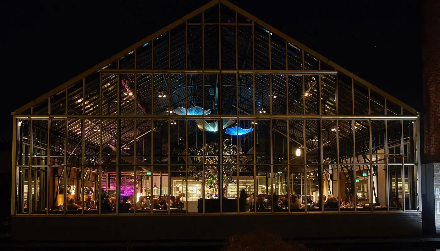 The glass greenhouse of De Kas restaurant in Amsterdam lit up at night