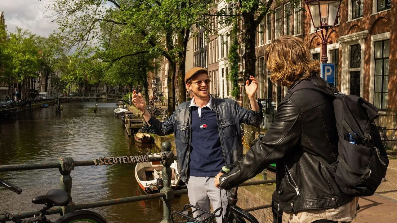Two men enjoying a bike ride together during a guided bike tour in Amsterdam.