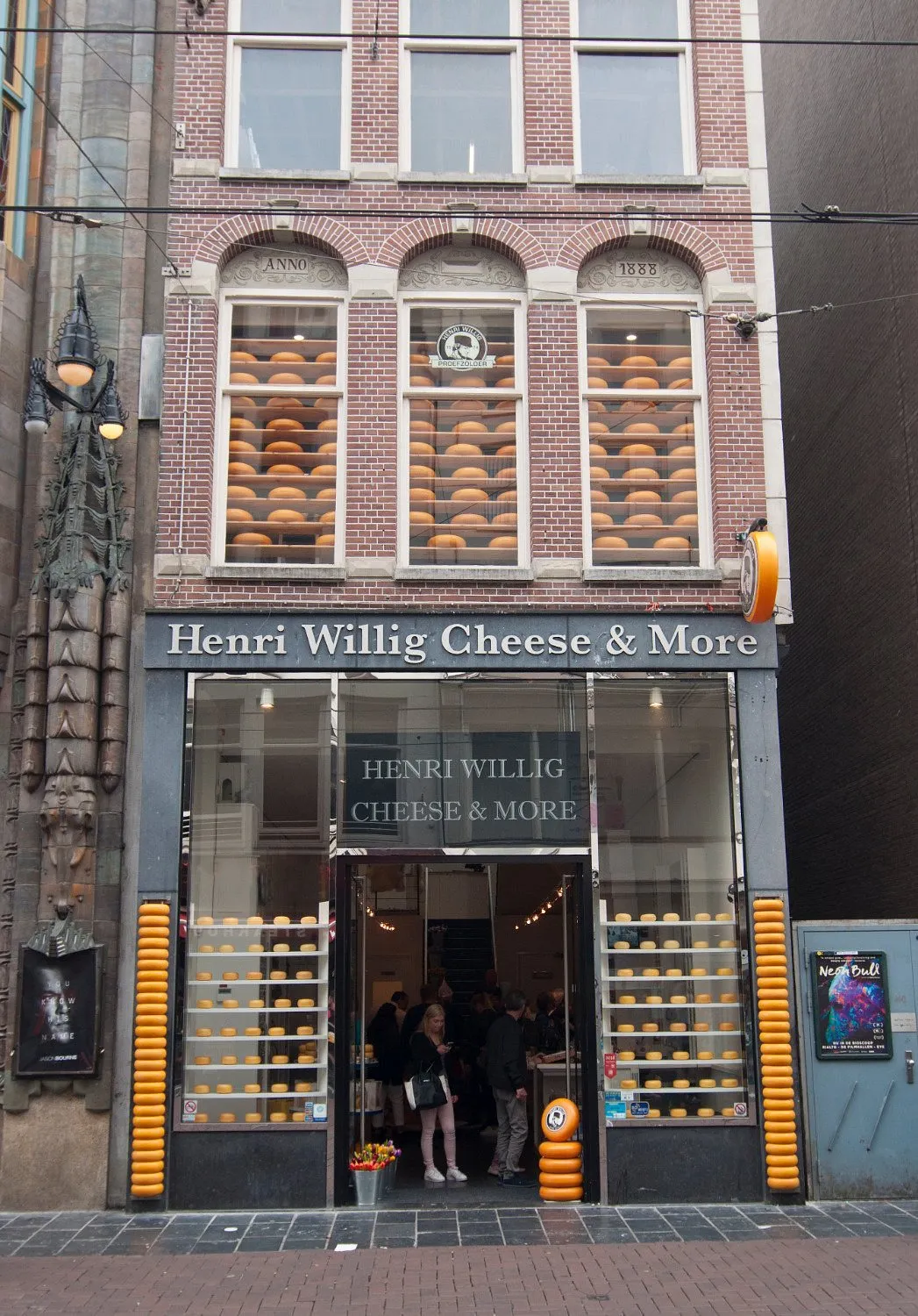Brick facade of the Henri Willig Cheese and More shop in Amsterdam with stacked yellow cheese wheels in every window
