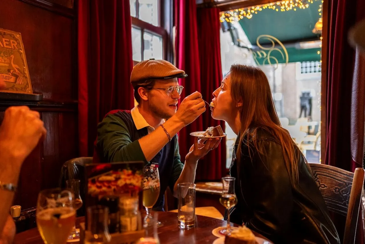 Local couple behind Adam & Eve Tours sharing dessert in a cozy Amsterdam brown cafe