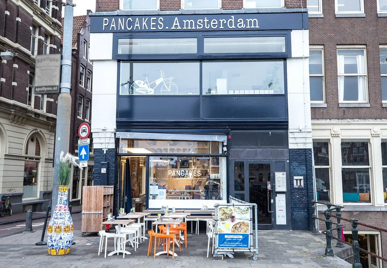 PANCAKES Amsterdam cafe seen from the street with empty terrace tables and a Delft style vase by the entrance